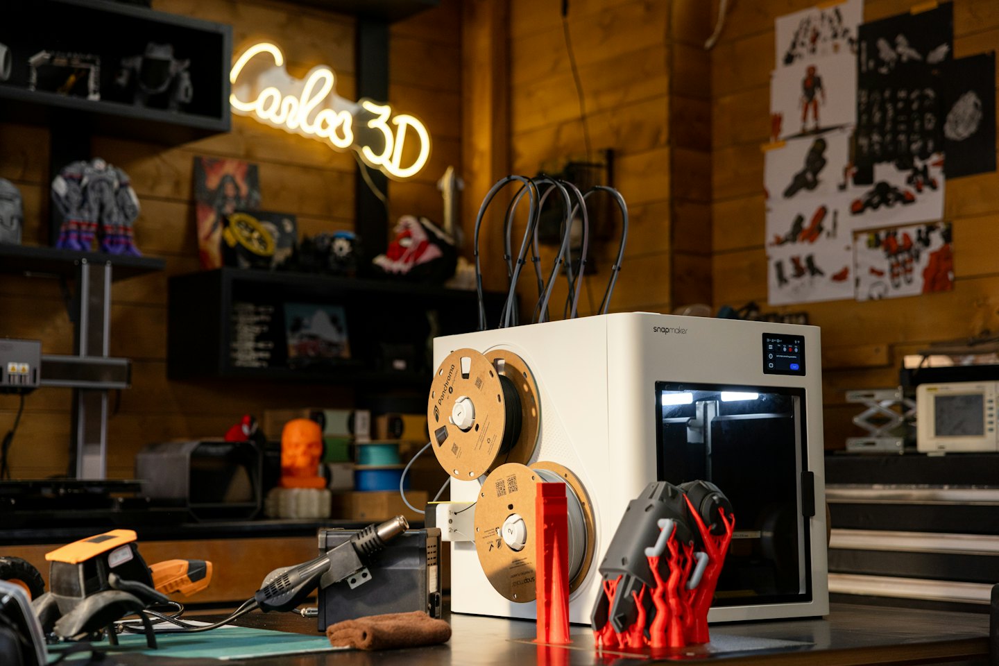Une imprimante 3D moderne crée un objet rouge sur un établi.